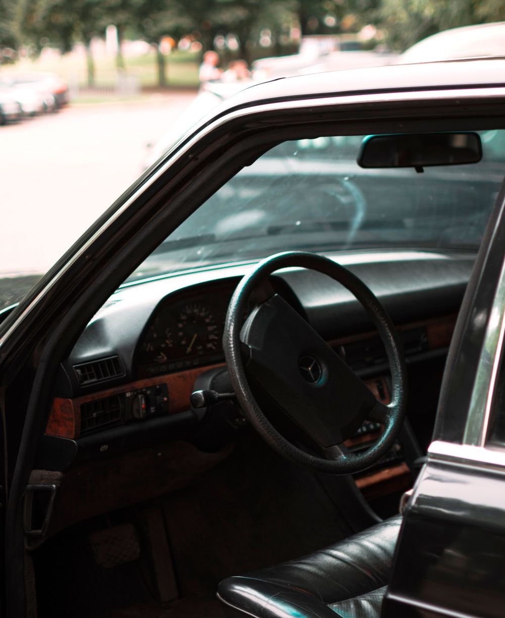Chauffeur holding a rear door open beside a black sedan on a Toronto street